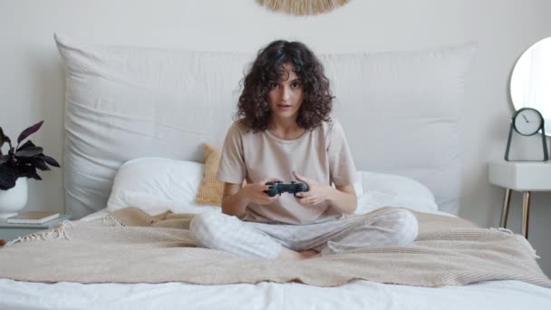 Feliz joven jugando videojuego con joystick ganando expresando felicidad en la cama en casa — Vídeos de Stock