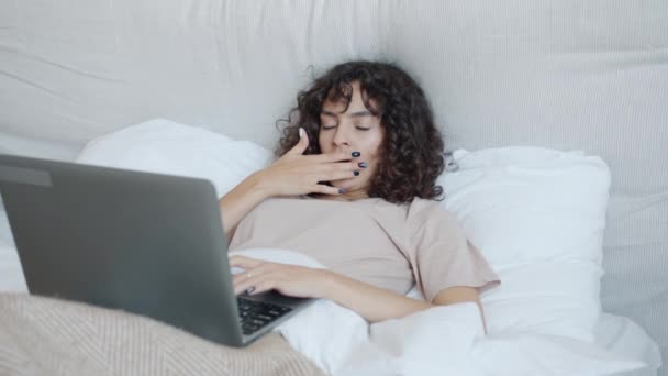 ベッドでラップトップコンピュータを使用して若い女性のフリーランサーを疲れその後、仕事の後に休んで眠る — ストック動画