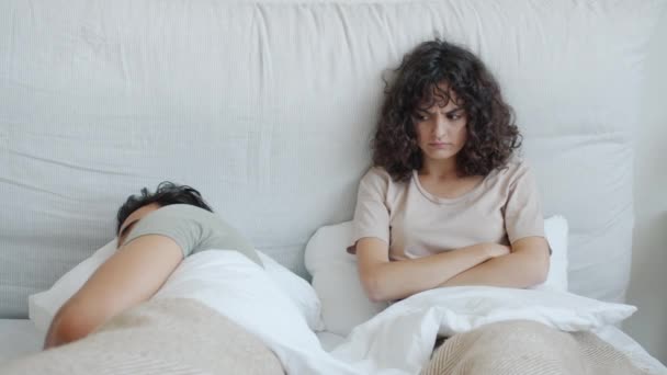 Irritado caucasiano mulher olhando para dormir marido árabe cara deitado no cama juntos — Vídeo de Stock