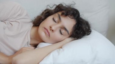 Sinirli kadın gürültüyle uyanır kulakları yastıkla kaplar huzursuzluk ve öfke hisseder.