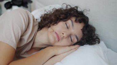 Gün boyunca rahat yastıkta uyuyan güzel bir kadının portresi.