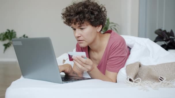 Jeune femme faisant du shopping à la maison effectuant un paiement en ligne avec ordinateur portable et carte de crédit se sentant malheureux — Video
