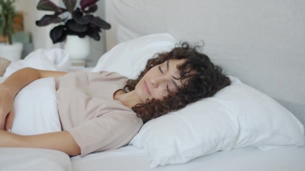 Vila flicka vakna på morgonen sträcker liggande i sängen och ler — Stockvideo