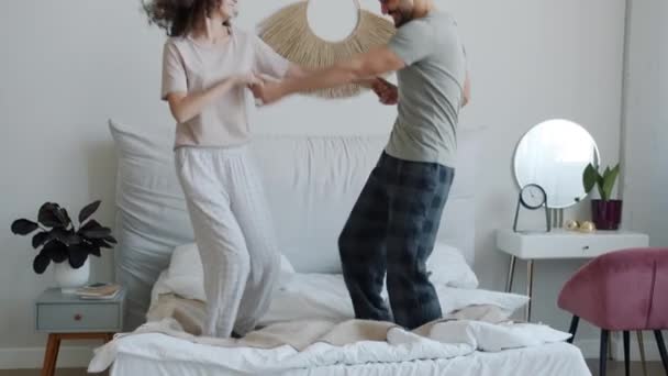 Zwolniony ruch arabskiego mężczyzny i białej kobiety w piżamie tańczących i śmiejących się w łóżku w domu — Wideo stockowe
