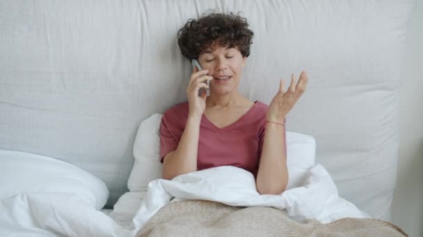 Porträtt av attraktiv flicka chatta på mobiltelefon sitter i sängen hemma — Stockvideo