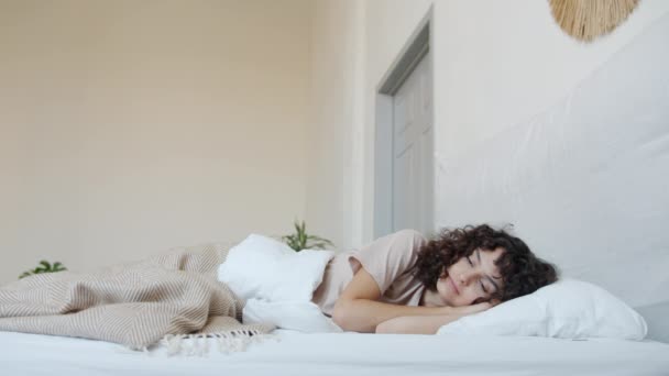 Porträtt av avslappnad ung dam vakna upp i bekväm säng leende stretching armar och kropp — Stockvideo