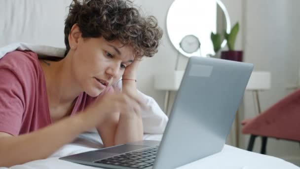 Malheureux jeune femme travaillant avec ordinateur portable dans le lit dactylographier puis éteindre l'ordinateur — Video