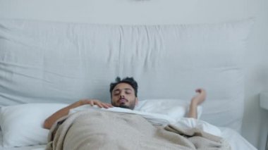 Yakışıklı Orta Doğulu bir adam uyuyor sonra esnemiş bedeniyle uyanıyor gülümsüyor.
