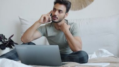 Uzaktan çalışan biri cep telefonundan arıyor ve evde çalışırken dizüstü bilgisayar kullanıyor.