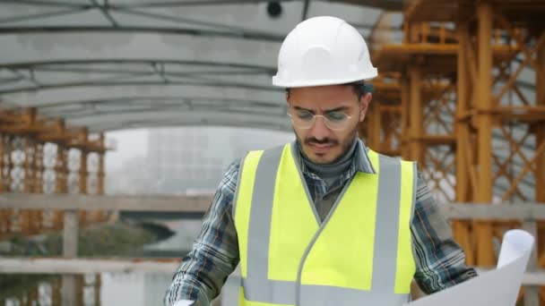 Serieuze Arabische man ingenieur controleren bouwplan en kijken rond buiten — Stockvideo