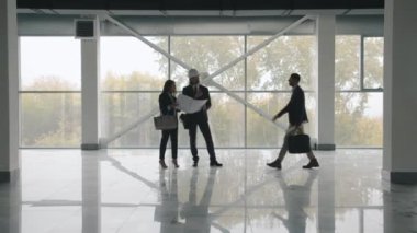 İş adamları yeni modern binanın içinde duran ve inşaat planını inceleyen emlak anlaşmasını tartışıyor