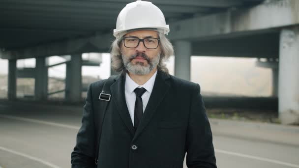 Tiszteletreméltó üzletember portréja a szabadban álló ipari zónában, biztonsági sisakban. — Stock videók