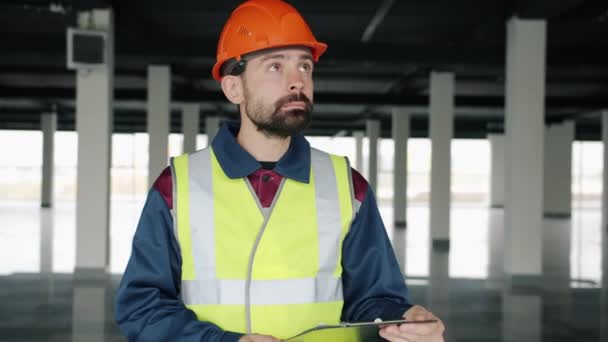 Inspector de construcción revisando papeles y estudiando edificio industrial dentro — Vídeo de stock