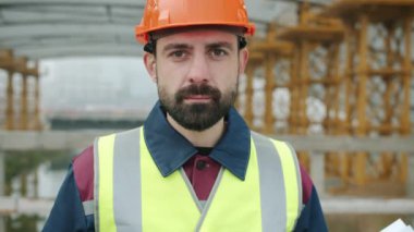 İnşaat alanında güvenlik üniforması giyen kendine güvenen işçinin portresi.