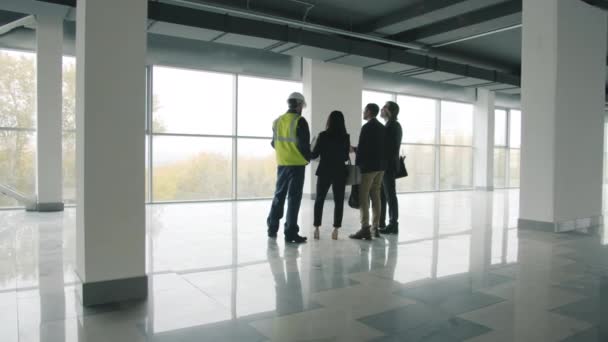 Diverso grupo de empresarios de pie dentro de un edificio industrial de nueva construcción hablando — Vídeos de Stock
