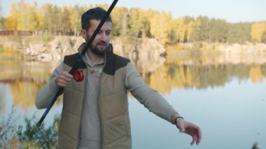 Çekici sakallı adamın portresi balık yakalıyor ve güzel arka planda gülümsüyor.