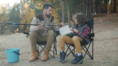 Bakıcı baba küçük oğluna balık tutmayı öğretiyor. Nehir kıyısında oltaları ve yemi tartışıyorlar.