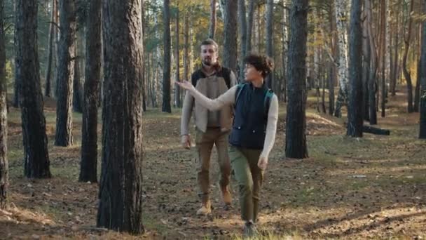 Dolly disparo de hermosa pareja joven caminando en el bosque y charlando admirando la naturaleza — Vídeos de Stock