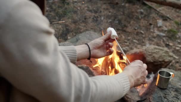 Gros plan des mains masculines mettant la guimauve sur le bâton et le dessert rôti sur le feu — Video