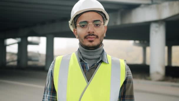 Портрет молодого араба в форме, стоящего в индустриальной зоне — стоковое видео