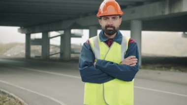 Arka planda inşaat sahasında duran kendinden emin ustabaşının portresi.