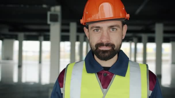 Slow motion portrait of builder in uniform looking at camera and nodding head smiling — Stock Video
