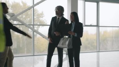 Yeni ofis merkezinde toplanan iş adamları ev kirasını tartışırken el sıkışıyor.