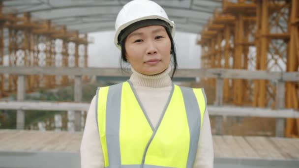 Retrato em câmera lenta do construtor feminino em pé fora da área de construção usando capacete de segurança — Vídeo de Stock