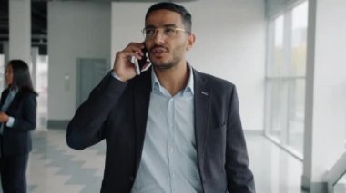 Yavaş çekimde emlak komisyoncusunun portresi yeni binanın içinde cep telefonuyla yürüme anlaşmasını tartışıyor.