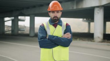 Sanayi bölgesinde kolları çapraz duran saha mühendisinin yavaş çekim portresi.