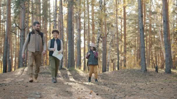 Familia feliz con niño caminando en el bosque senderismo estudiando mapa y hablando — Vídeos de Stock