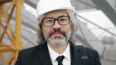 Bina yöneticisinin miğfer takarak dışarıda dikilirken yavaş çekim portresi