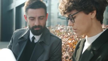 Motive olmuş iş adamları güneşli bir sonbahar gününde sokak kafesinde oturup sözleşmeleri tartışıyorlar.
