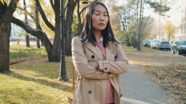 Retrato en cámara lenta de una mujer asiática confiada parada al aire libre en la ciudad con los brazos cruzados — Vídeos de Stock