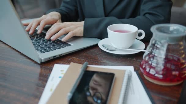 Női kéz közelkép gépelés laptop billentyűzeten, miközben üzletasszony dolgozik a kávézóban — Stock videók