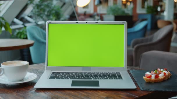 먹을 것 과마실 것이 있는 카페 탁자 위에 있는 현대 크로마 키 녹색 스크린 노트북의 근접 사진 — 비디오