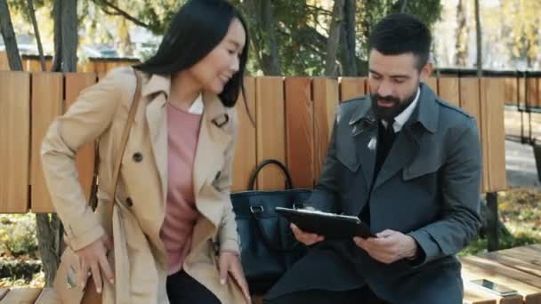 Kaukasisk affärsman möte asiatisk affärskvinna skakar hand diskuterar papper utomhus — Stockvideo