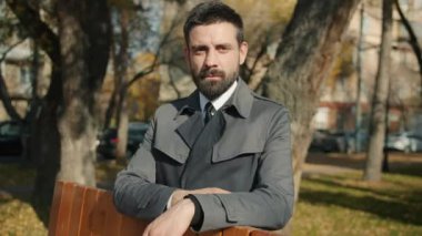 Çekici sakallı adamın yavaş çekimde çekilmiş bir portresi dışarıda kameraya bakıyor.