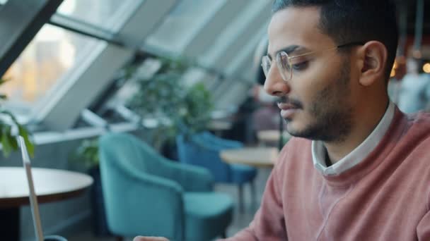 Retrato de inclinação para baixo em câmera lenta do ambicioso cara do Oriente Médio trabalhando com laptop no café — Vídeo de Stock