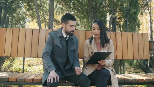 İş ortakları erkek ve kadın sonbahar parkında şirket evraklarını tartışıyor. — Stok video