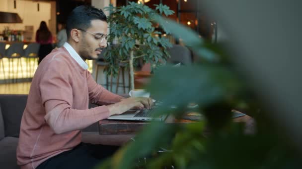 Kafede dizüstü bilgisayarla yazı yazan ciddi Arap girişimcinin yavaş çekim portresi — Stok video