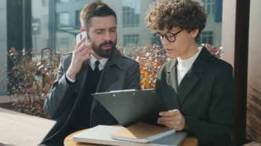 Hırslı iş adamı cep telefonuyla konuşuyor ve kadın meslektaşına danışmanlık yapıyor.