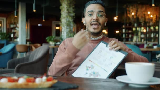 Retrato del hombre de negocios árabe haciendo informe durante la videollamada en línea en la cafetería — Vídeo de stock