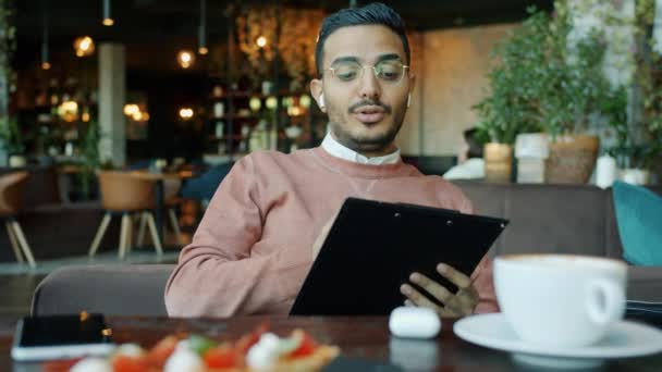Empresário motivado conversando e mostrando papéis durante videochamada do café moderno — Vídeo de Stock
