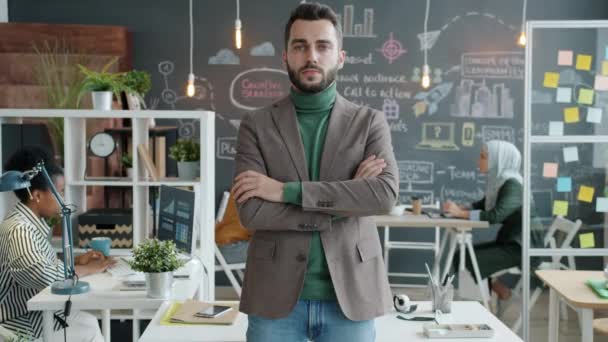 Retrato em câmera lenta de cara ambicioso em roupa elegante em pé no escritório com os braços cruzados — Vídeo de Stock