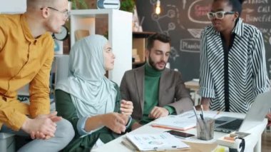 Ofiste yapılan gayri resmi toplantıda konuşan ve gülümseyen çeşitli iş adamları.