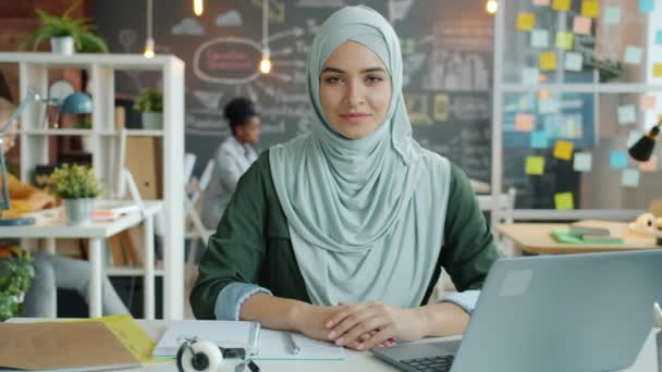 Retrato en cámara lenta de una hermosa mujer musulmana en hijab sentada en el escritorio del trabajo — Vídeos de Stock