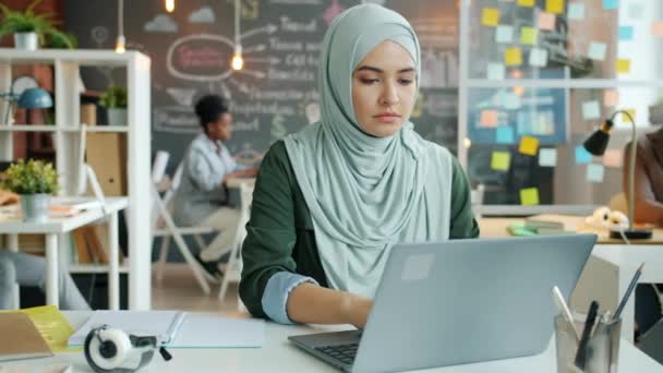 Retrato de una exitosa mujer musulmana en hijab trabajando con computadora portátil escribiendo en el escritorio — Vídeos de Stock