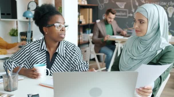 Női irodai dolgozók muszlim és afro-amerikai üzleti ötletek megosztása nézi laptop képernyő munkahelyi — Stock videók