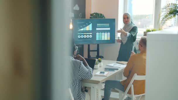 Meslektaşlar için sunum sırasında tesettürlü Müslüman kadın konuşuyor ve dijital ekrana işaret ediyor — Stok video